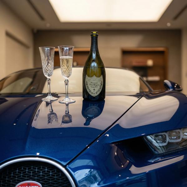 Crystal champagne flutes on hypercar hood, symbolizing luxury celebration.