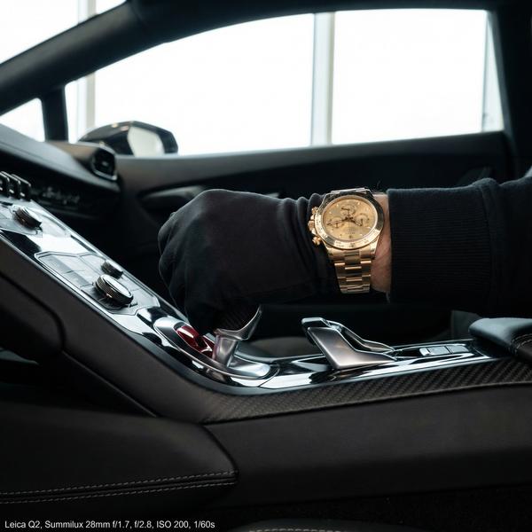 Detail shot of gold watch and gearshift, epitomizing luxury craftsmanship.