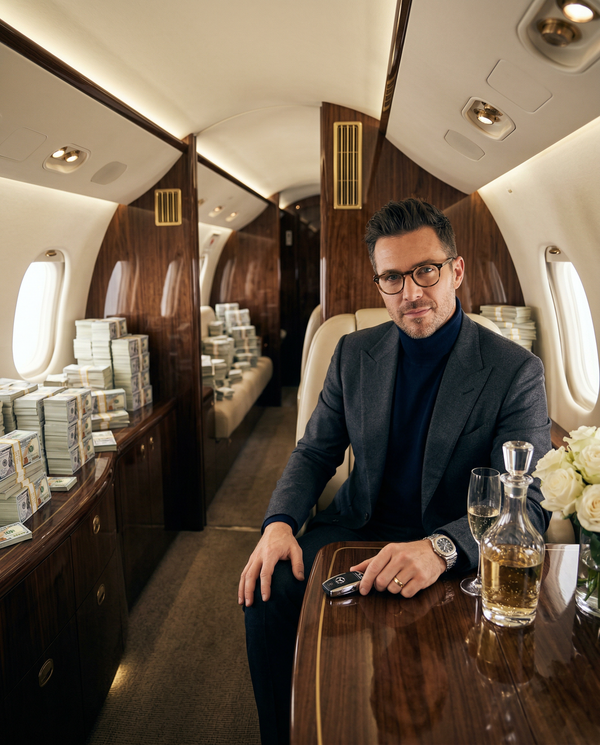 Executive in private jet cabin seated among towers of cash
